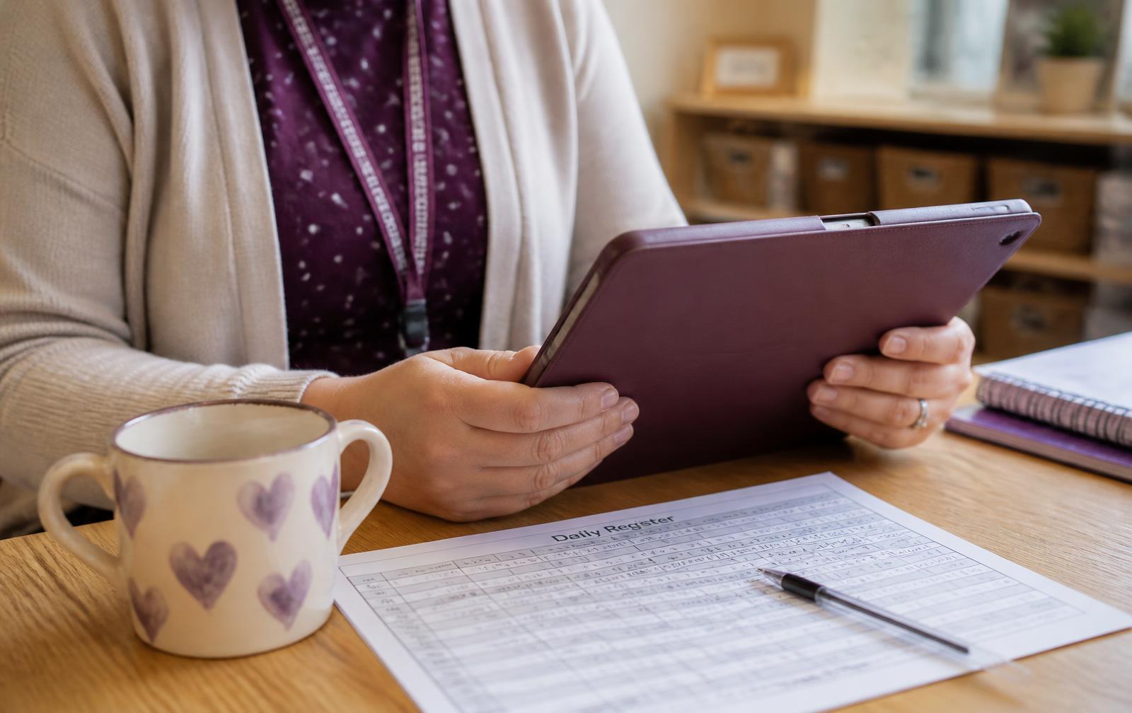 A practitioner's hands holding a tablet at child height, recording something while standing in the room.
